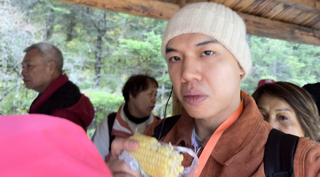 Me eating corn while queueing for the cable car - Jiuzhaigou and Huanglong Ultimate 3 Days Travel Guide - Leo Trails