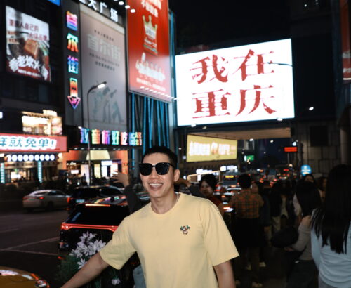 Me posing at Wǒ zài Chóngqìng (我在重庆) Billboard - Ultimate Chongqing Itinerary: 7 Top Attractions - Leo Trails