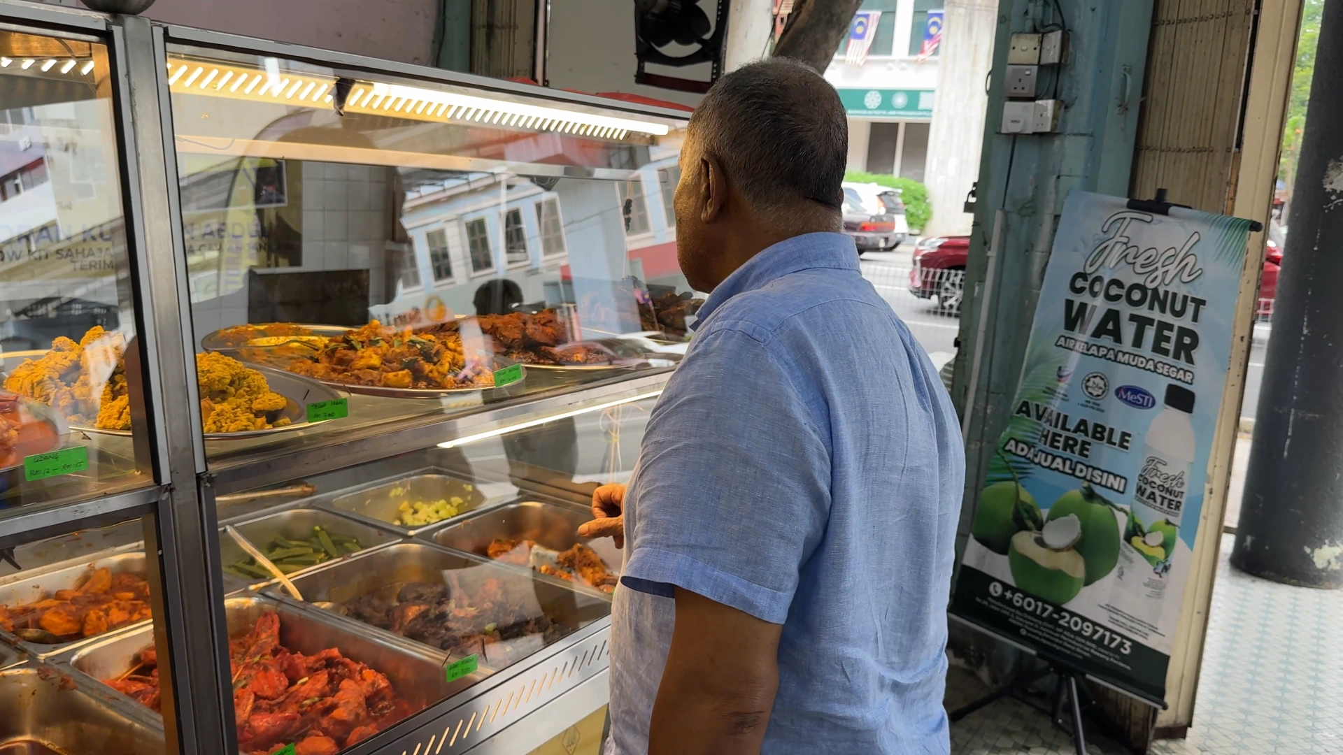 a man is still looking what to eat here -Try KL Dishes That Locals Love - leo trails