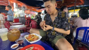 Me trying to eat Banh Can - Son Tra Night Market Da Nang: Food & Things to Do - Leotrails