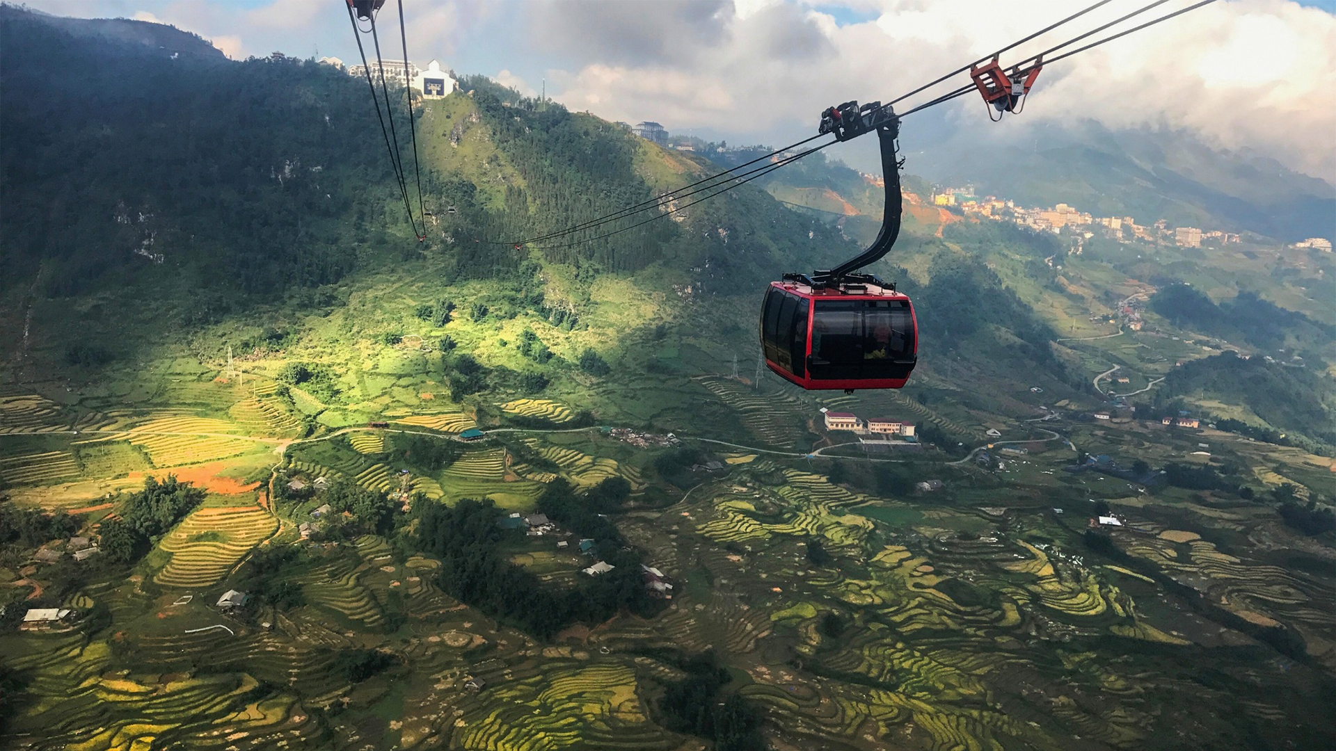 A Fansipan red cable car atop of rice paddy fields - How to Buy Fansipan Mountain Tickets the Easy Way 🎟️ - Leotrails