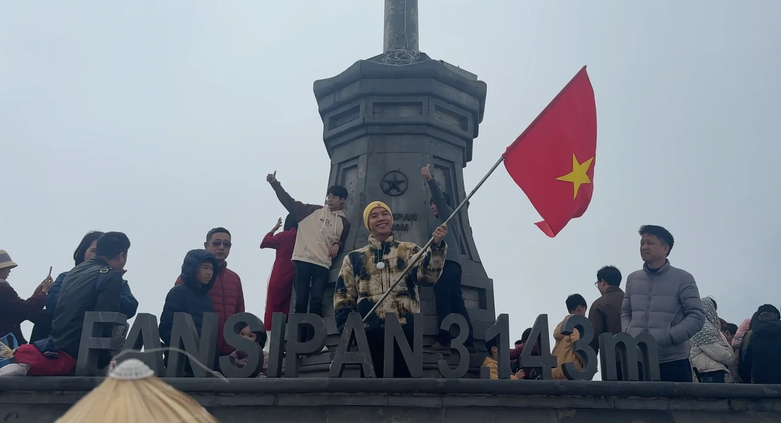 Waving the Vietnam flag on the top of Fansipan Mountain - How to Buy Fansipan Mountain Tickets the Easy Way 🎟️ - Leotrails