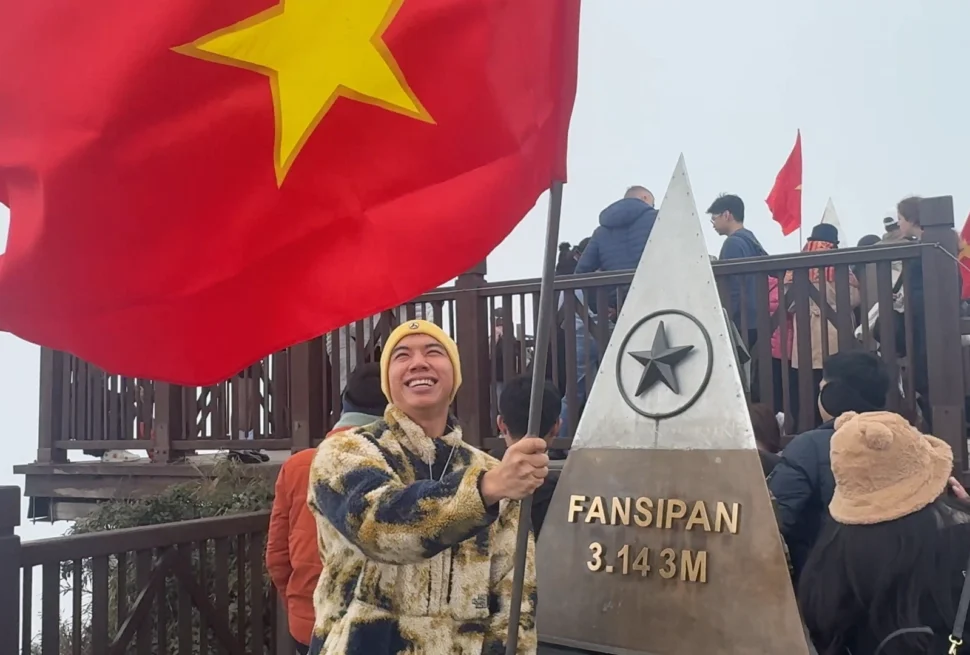Me waving a vietnam flag at Fansipan Mountain Monument - How to Buy Fansipan Mountain Tickets the Easy Way 🎟️ - Leotrails