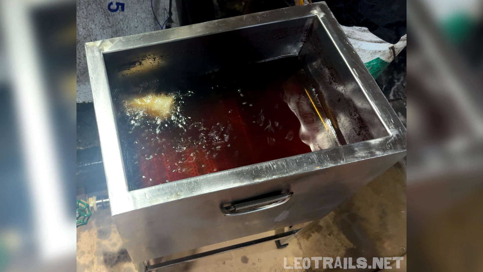 A stainless steel commercial deep fryer filled with hot oil, cooking crispy Vietnamese spring rolls (Nem Rán)