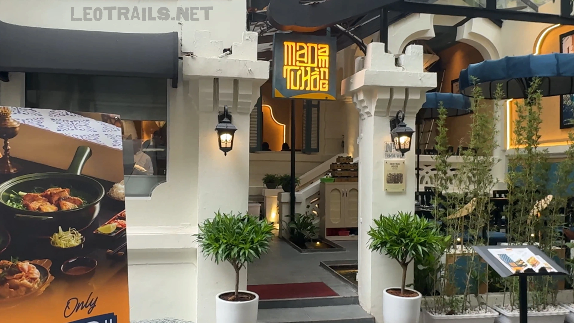 Exterior view of Madam Tuấn restaurant entrance with outdoor seating details.