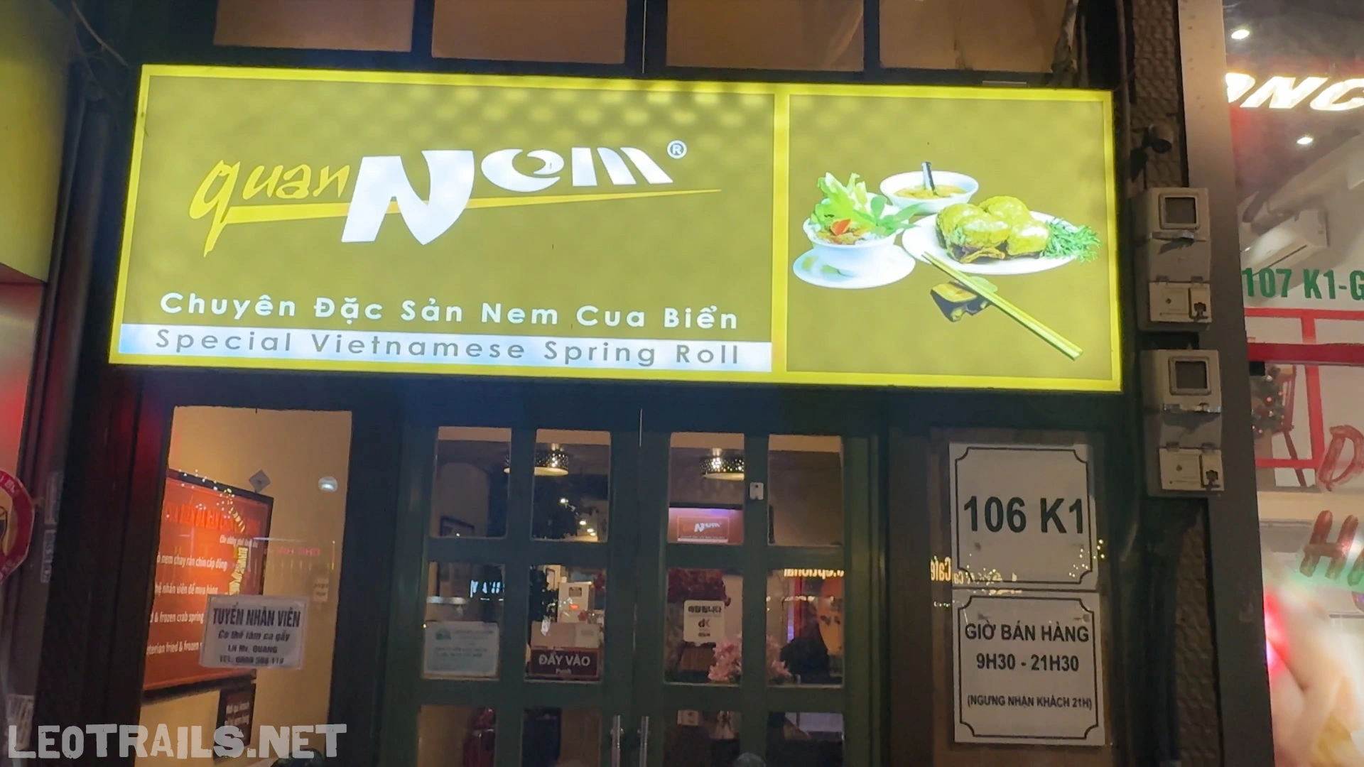 The street-facing storefront of Quán Nem restaurant at 106 K1, showing a glowing yellow sign that reads "quán Nem - Chuyên Đặc Sản Nem Cua Biển - Special Vietnamese Spring Rol