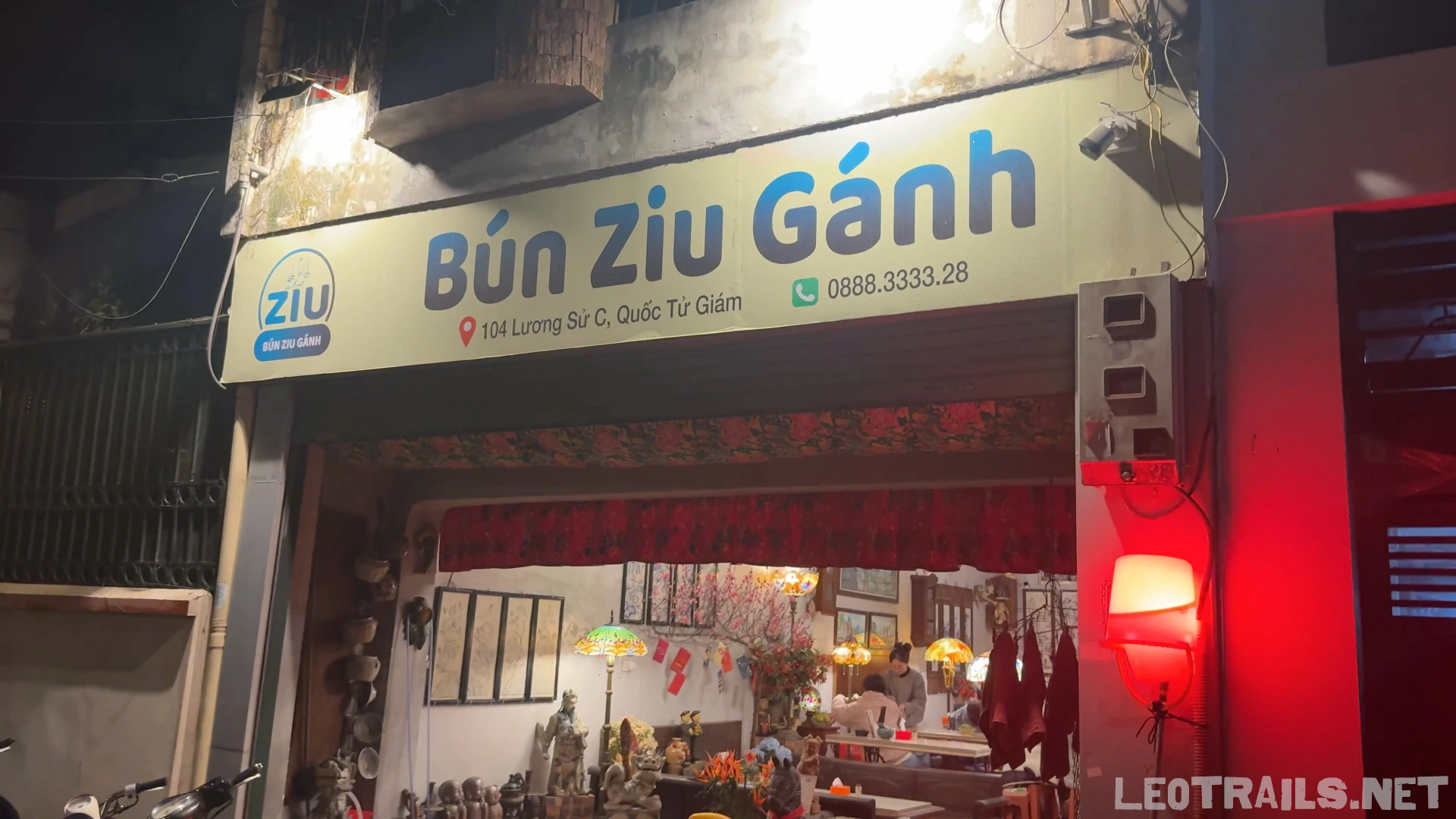 The street-facing storefront of Bún Ziu Gánh restaurant at 104 Lương Sử C in Hanoi, featuring a prominent white signboard with blue and yellow lettering that reads "Bún Ziu Gánh".